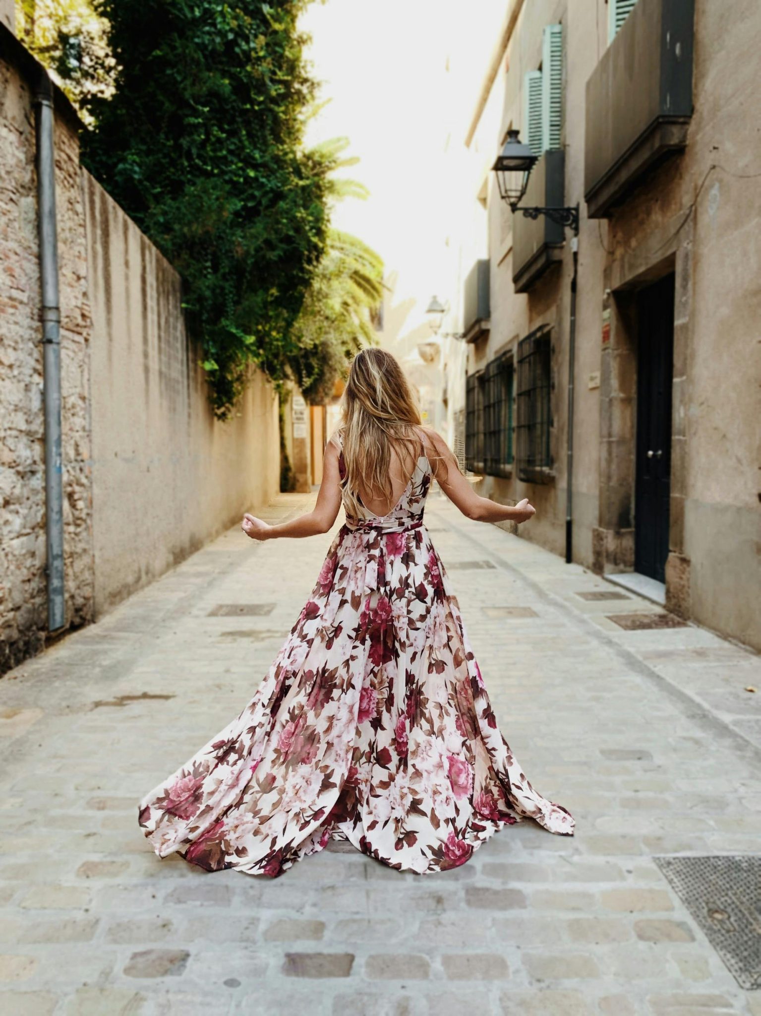 Woman wearing white and pink floral bridesmaid dress standing on alley