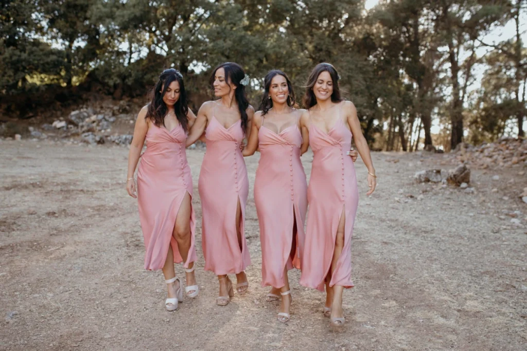Four bridesmaids in pink dresses with trees in the background