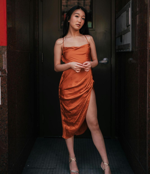 Woman in orange dress posing.