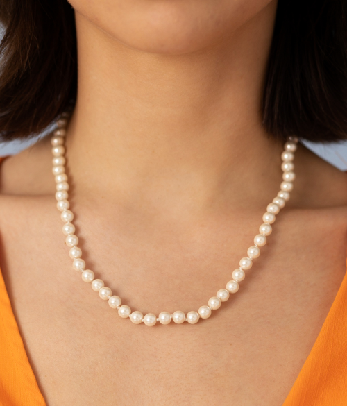 Close-up of pearl necklace on neck.